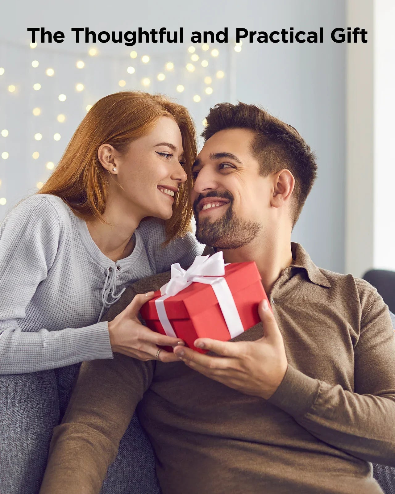 Couple exchanging a gift with a red box and white ribbon, surrounded by warm lighting.
